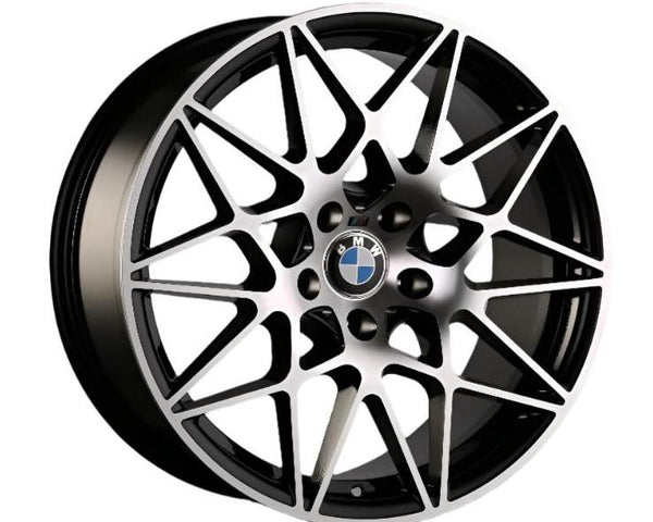 A multi-spoke alloy wheel with geometric patterns features the BMW logo at the center. It has a metallic finish and is designed for automotive use.