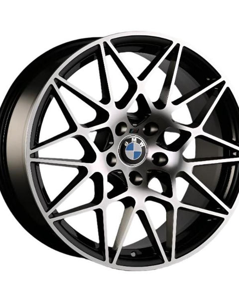 A multi-spoke alloy wheel with geometric patterns features the BMW logo at the center. It has a metallic finish and is designed for automotive use.