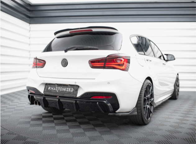 A white, sporty sedan with tinted windows is parked in a modern garage. The car has black alloy wheels, dual exhaust, and a "#MAXTONIZED" license plate on a patterned floor.