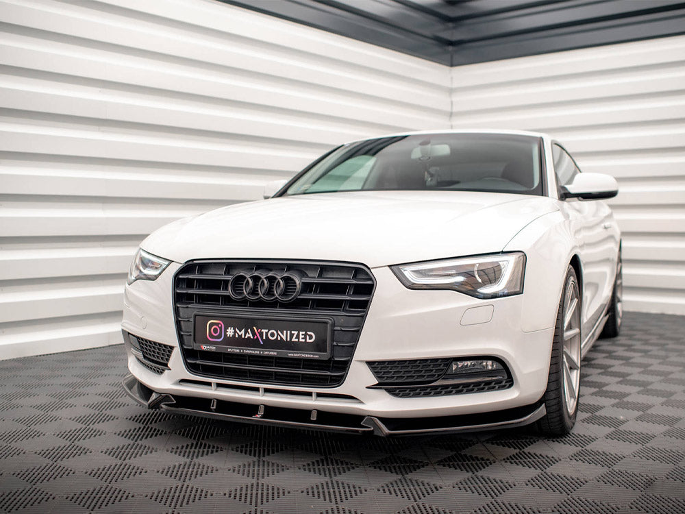 A white car is parked, featuring a prominent grille with a logo, in a modern, striped white and gray room. The license plate reads "Instagram #MAXTONIZED."