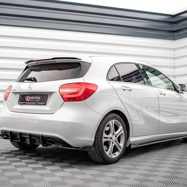A white hatchback car is parked indoors on a checkered floor. It features red tail lights and a rear spoiler. Visible text on the license plate reads: "MAXTON design."