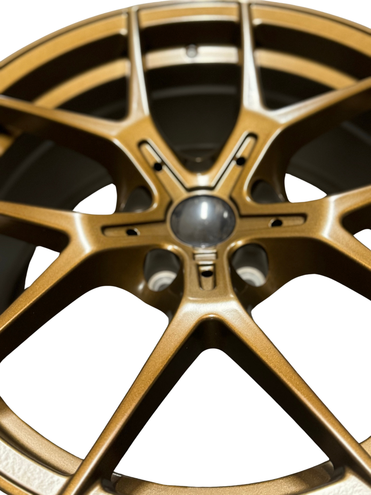 A bronze-colored alloy wheel with multiple spokes is positioned against a plain white background, emphasizing its intricate design and metallic finish.
