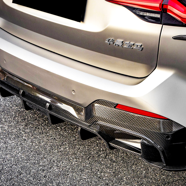 Car rear with a carbon fiber diffuser, parked on asphalt. "华晨宝马" text on the back, red taillights illuminated, set in bright daylight.