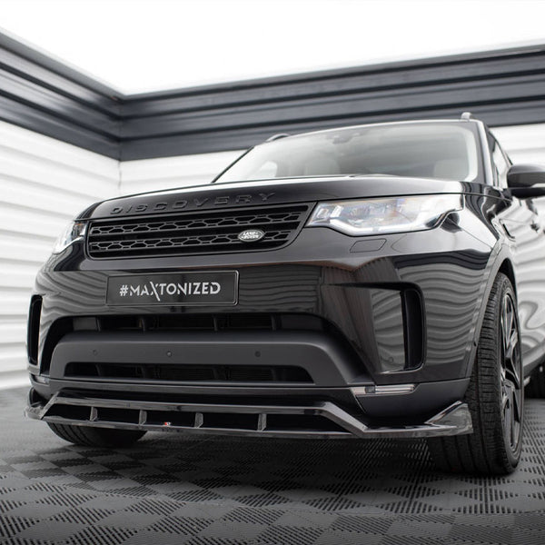 A black SUV, labeled "DISCOVERY," is parked in a modern garage. The license plate reads "#MAXTONIZED." The environment has checkered flooring and striped walls.