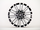 A shiny black and silver alloy wheel with a Volkswagen logo in the center is displayed against a plain white background.
