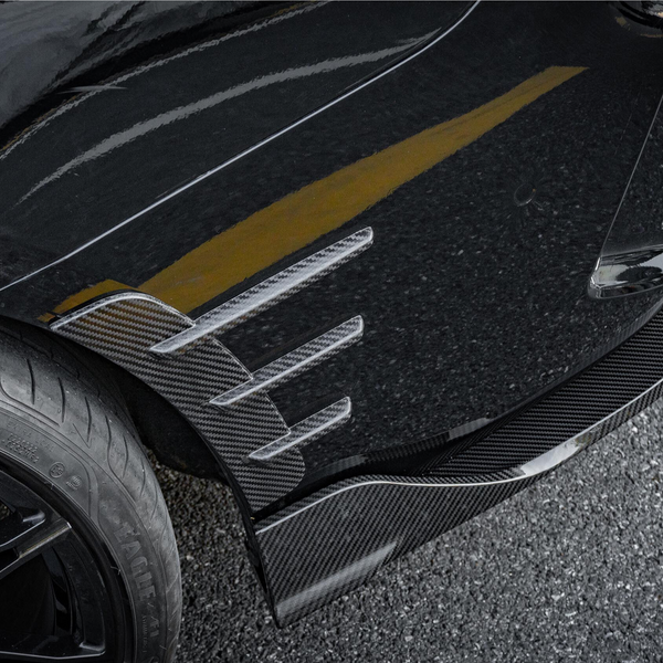 A car tire with a black alloy wheel is parked on asphalt. The vehicle features carbon fiber aerodynamic fins and a glossy black surface, reflecting a yellow line. Text: "MADE IN GERMANY RADIAL TUBELESS."