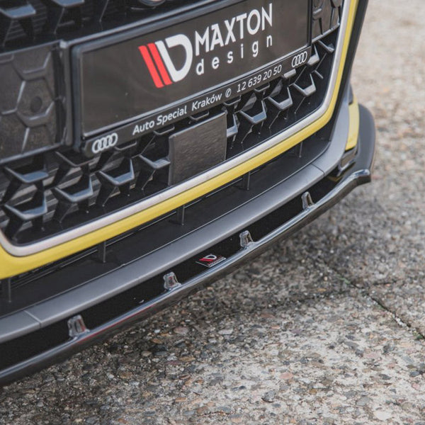 Car front bumper with a Maxton design plate featuring Audi's logo; it rests on a textured, concrete surface. Text: "MAXTON design," "Auto Special Kraków," and "12 639 20 50."