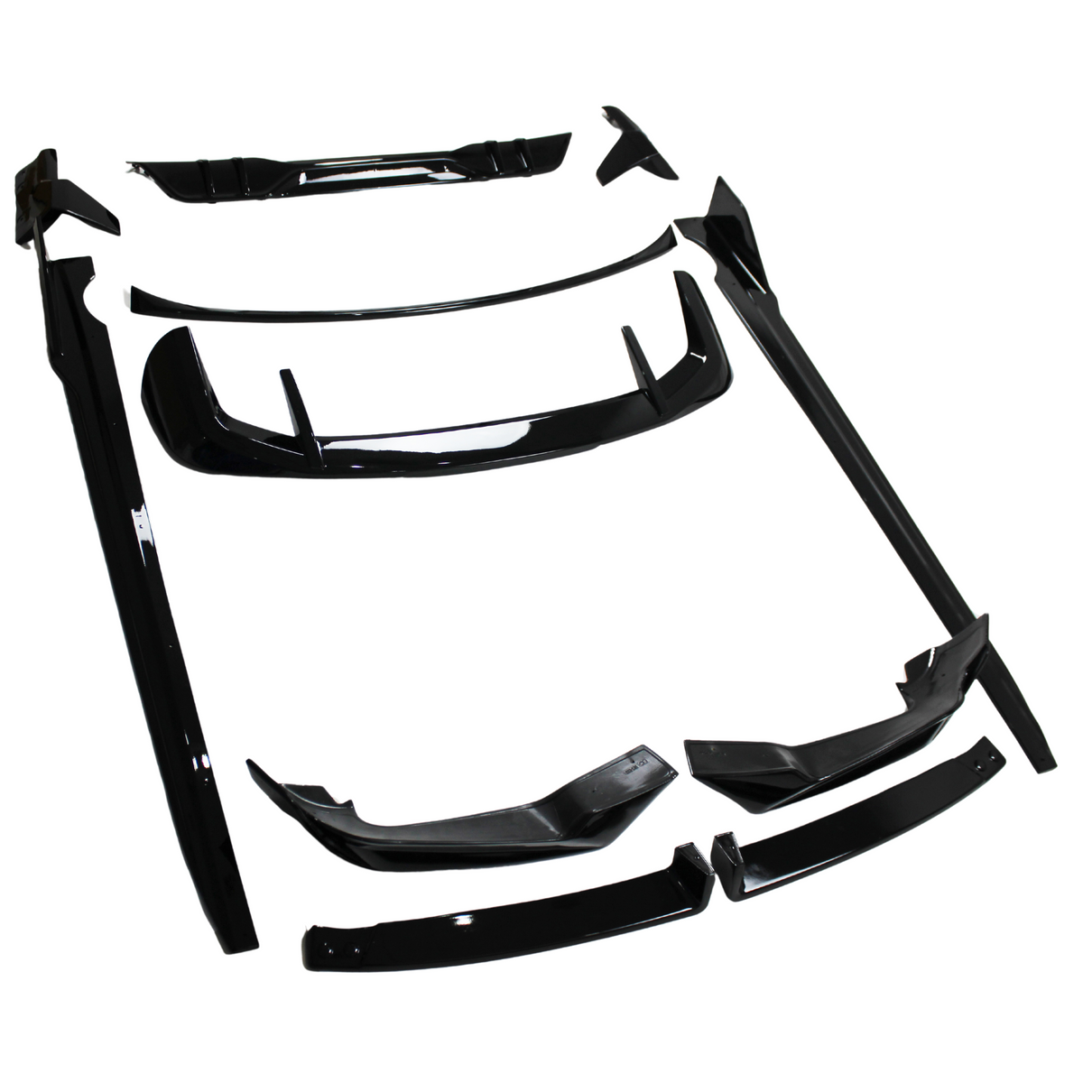Black automotive body kit parts laid out on a white surface; several pieces include spoilers, skirts, and bumpers, all designed for vehicle modification.