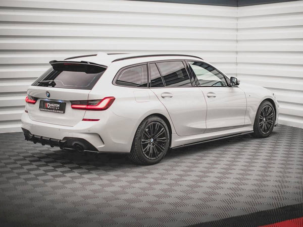 A white BMW station wagon is parked on a checkered floor in a bright, modern showroom. The license plate reads "DARITON DESIGN."