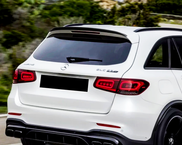 A white SUV drives on a road with surrounding greenery. Text on the vehicle reads "GLC 63S" and "AMG" near the Mercedes logo.