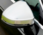 A silver car side mirror features an integrated turn signal, attached to a black vehicle door in daylight.