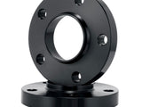 A black metal flange with multiple bolt holes lies flat, while another identical flange stands vertically, both set against a plain white background.