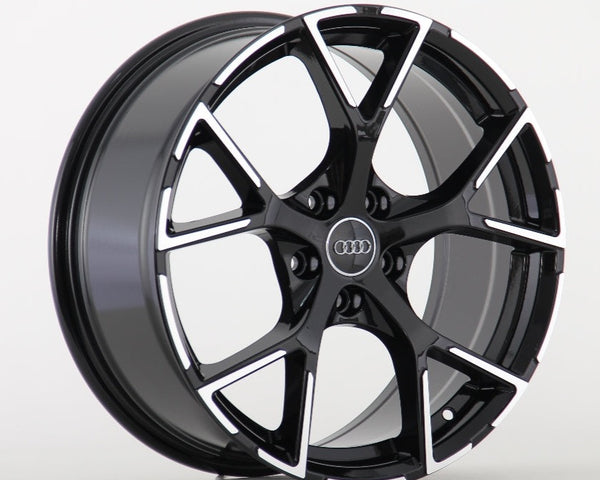 A black and silver alloy wheel with a five-spoke design, prominently featuring the Audi logo in the center, is displayed against a plain white background.