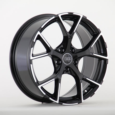 A black and silver alloy wheel with a five-spoke design, prominently featuring the Audi logo in the center, is displayed against a plain white background.