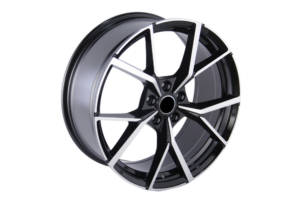 A black and silver alloy wheel with angular, geometric spokes, positioned at an angle against a plain white background.