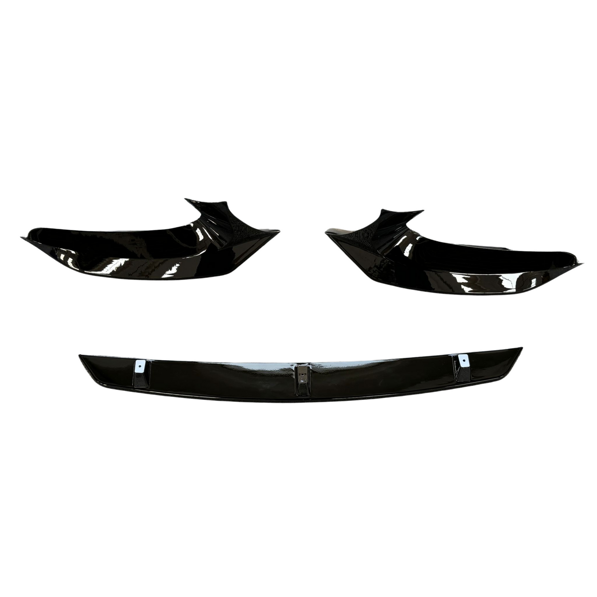 Three glossy black car body parts are displayed against a white background, featuring two angular side components and a straight centerpiece below, resembling a front splitter set.