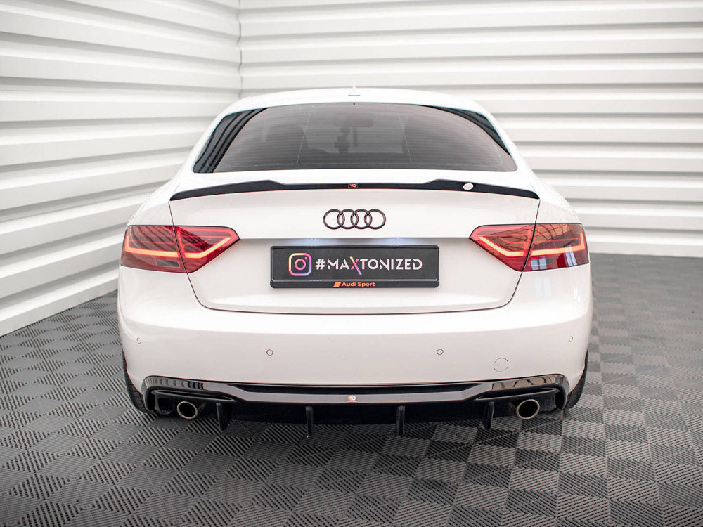 White car parked in a grid-patterned room, highlighted by the rear view with red taillights and dual exhausts. License plate reads "#MAXTONIZED Audi Sport" with an Instagram logo.