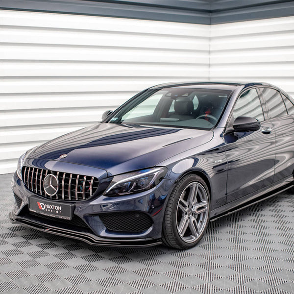 A dark blue sedan parked indoors on a checkered floor, featuring a prominent grille and alloy wheels. The license plate reads "HAXTON design." The wall is ridged with white panels.