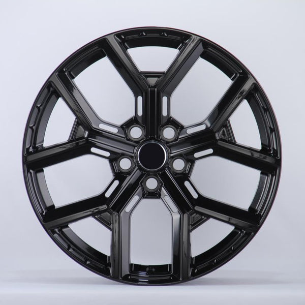 Black, glossy, multi-spoke alloy wheel; resting upright in a well-lit studio setting; casting a slight shadow on the white background.