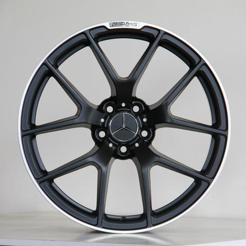 A black alloy wheel with a Mercedes-Benz logo is centered against a light background. It has a sleek multi-spoke design and displays the text "AMG" at the top.
