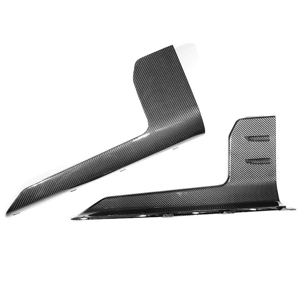Two carbon fiber car accessories, possibly side skirts, lie against a plain white background. The pieces display a sleek, modern design with a diagonal striped pattern.