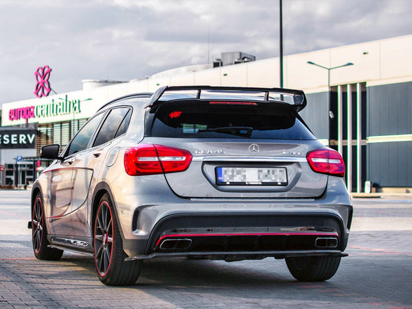 A silver Mercedes-Benz A45 AMG parked in a shopping center lot, featuring spoiler and red accents. Background shows buildings with "europa centralna" signage and cloudy sky.