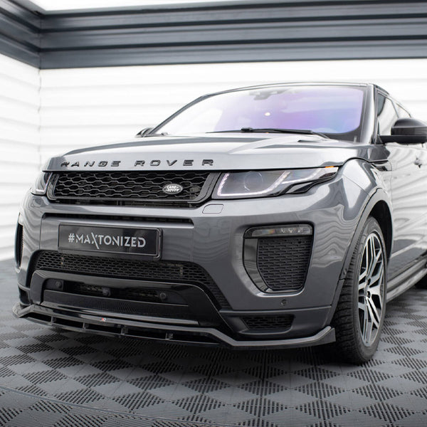 A gray Range Rover is parked in a garage with checkered flooring. The front bumper features a "#Maxtonized" license plate. The vehicle is positioned in front of white panel walls.