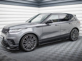 A sleek gray SUV is parked in a modern showroom with textured walls. It's a Range Rover, featuring large alloy wheels and a stylish, streamlined design.
