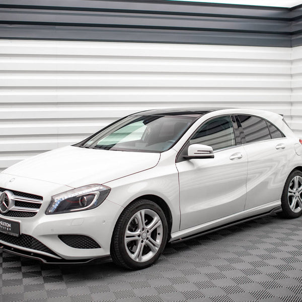A white Mercedes-Benz hatchback is parked in a modern showroom with sleek, textured walls. A sign on the front reads "D'AXTON DESIGN."