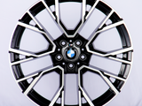 The object is a car wheel rim with a sleek, multi-spoke, black-and-silver design, displaying a BMW emblem in the center. The context is a plain, white background.