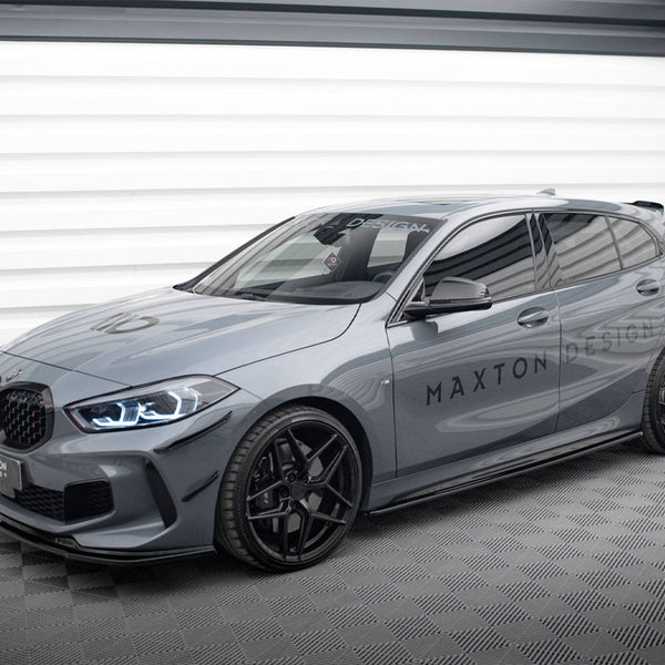 A sleek gray hatchback car with sporty black wheels is parked in a well-lit garage. The words "MAXTON DESIGN" are prominently displayed on its side and windshield.