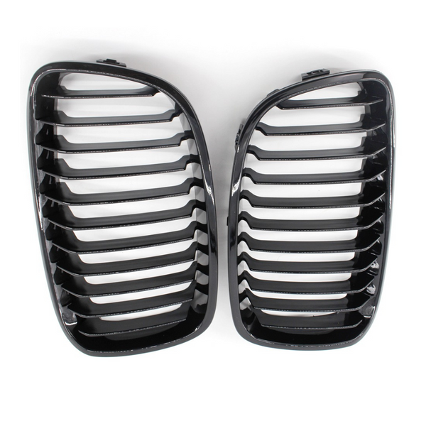 Two glossy black car grilles with horizontal slats are placed side by side against a plain white background.