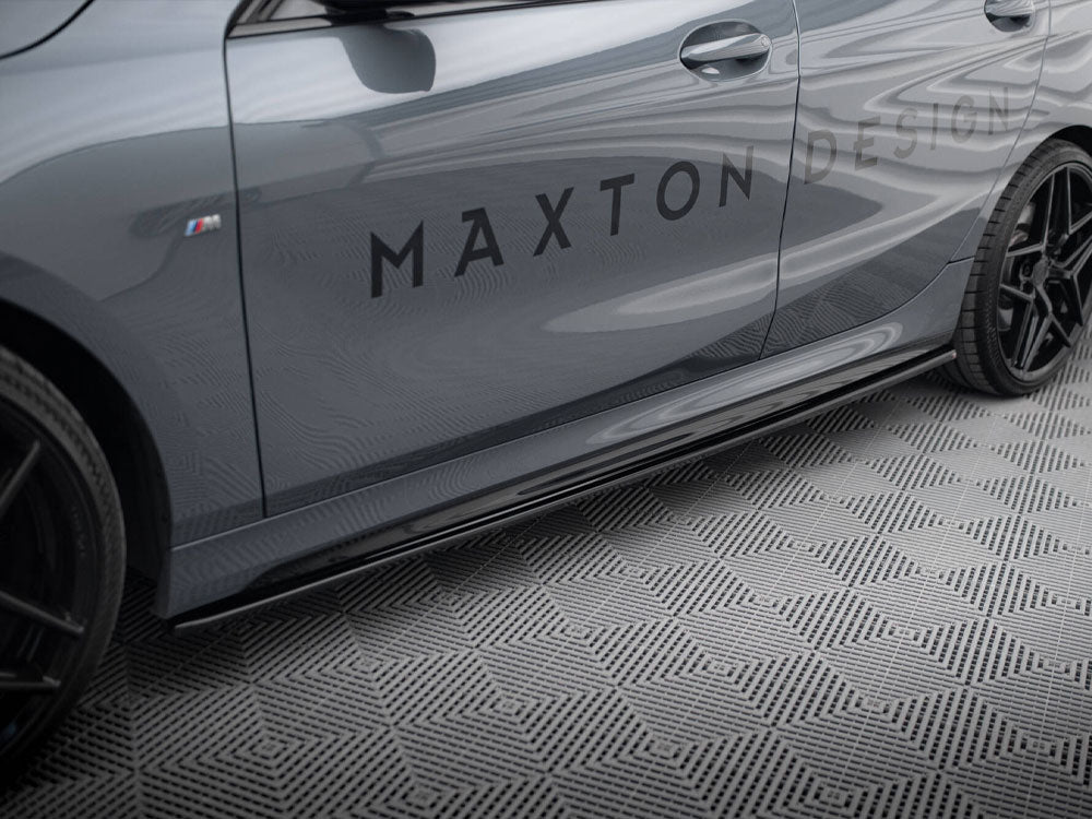A sleek grey car, stationary, displays the text "MAXTON DESIGN" on its side, set on a textured geometric-pattern floor. Black wheels and sporty styling enhance its modern appearance.