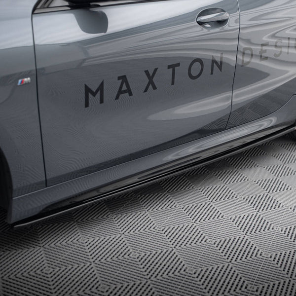 A sleek grey car, stationary, displays the text "MAXTON DESIGN" on its side, set on a textured geometric-pattern floor. Black wheels and sporty styling enhance its modern appearance.