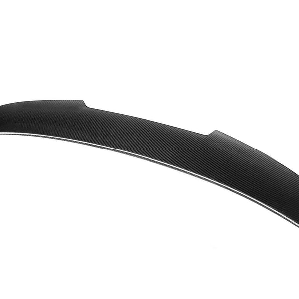 A sleek, curved black car spoiler lies against a plain white background, showcasing its aerodynamic design and textured surface.