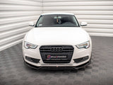 A white Audi car is parked in a patterned indoor space with textured floors and walls. The front license plate displays 