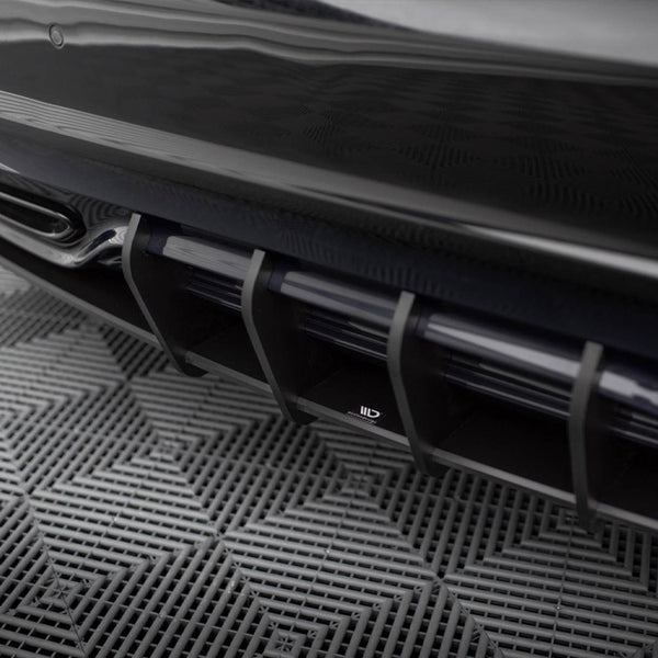 A sleek car diffuser with vertical slats at the rear, positioned above a textured, grid-patterned floor.