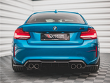 A blue BMW car is stationary, rear-facing, with dual exhausts visible. It bears the text 