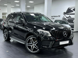 A black SUV is parked indoors, featuring a sleek design and alloy wheels. The setting is a showroom with white walls and a car illustration. Text on the wall reads, 