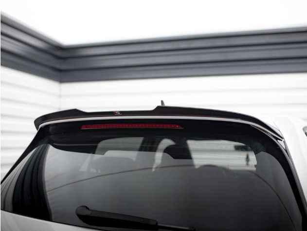 A car's rear window with a spoiler and brake light is parked in a garage. The walls are lined with horizontal white and black panels, creating a modern, enclosed space.
