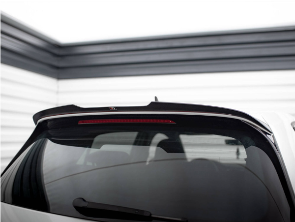 A car's rear window with a spoiler and brake light is parked in a garage. The walls are lined with horizontal white and black panels, creating a modern, enclosed space.
