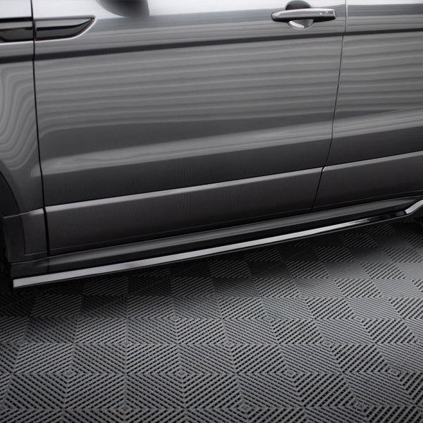 A grey SUV side, with polished metallic running boards, is parked on a patterned floor. The vehicle has clean lines and sleek wheel rims, indicating a modern design.