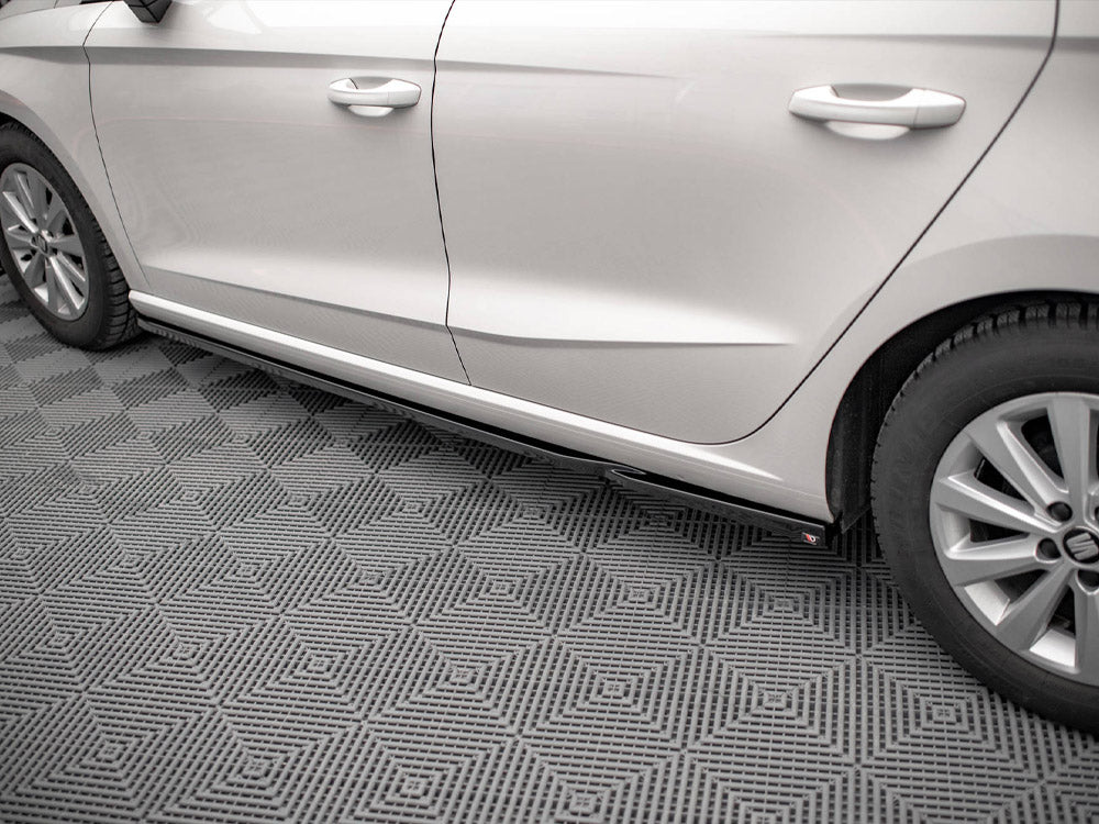 Car parked on a textured gray floor, showing the side doors and tires, with a visible step below the doors. No text is present.