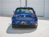A blue Volkswagen car is parked on a concrete surface, with dual exhausts and a 