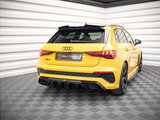A yellow Audi RS3 is parked in a showroom with a geometric floor and white walls. The license plate reads 