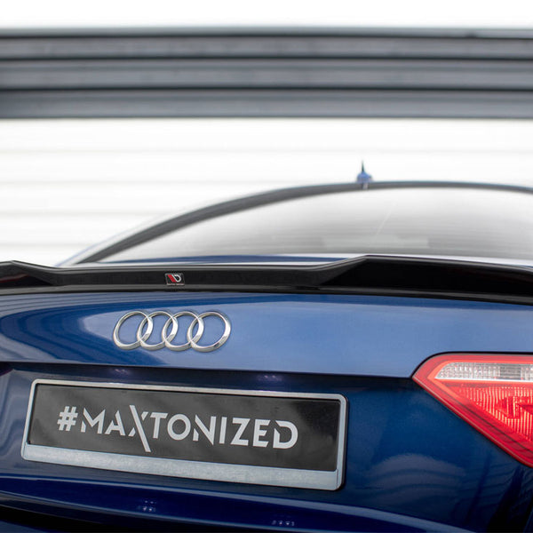 A blue Audi A5 features a black spoiler on its rear, parked in front of a striped garage door. The license plate reads "#MAXTONIZED".