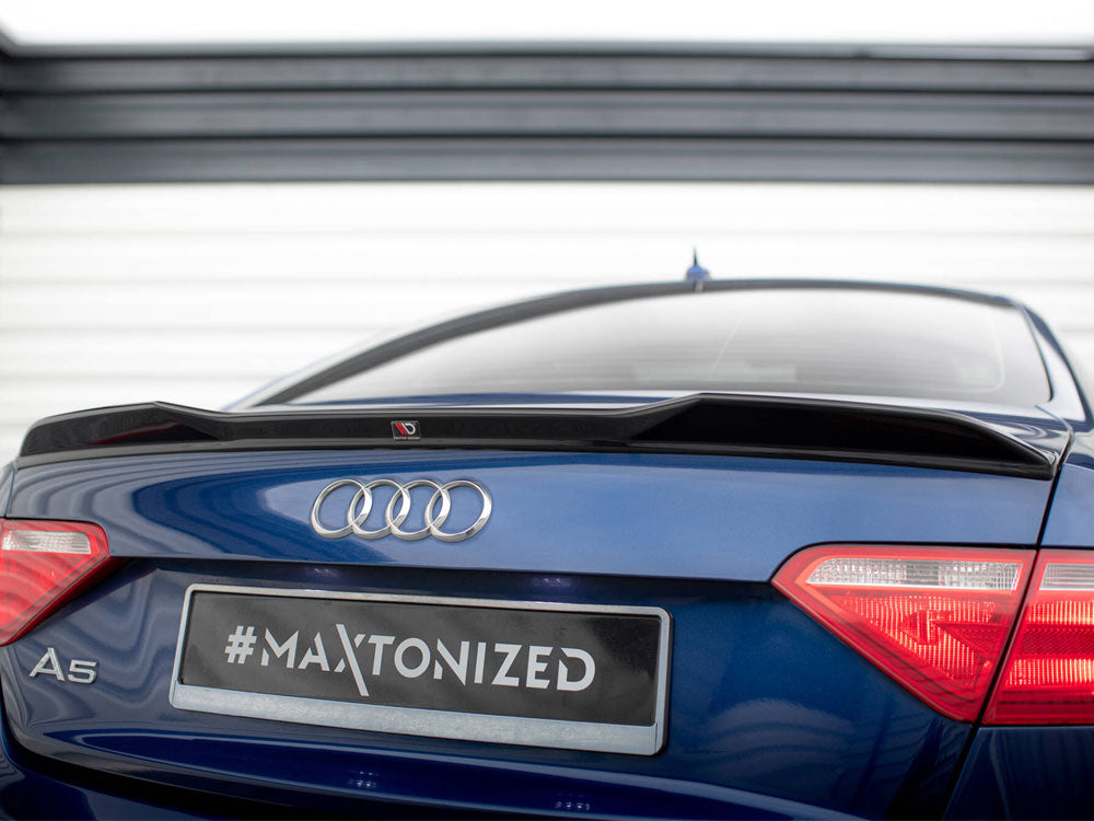 A blue Audi A5 features a black spoiler on its rear, parked in front of a striped garage door. The license plate reads "#MAXTONIZED".