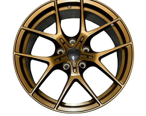 A bronze alloy car wheel rim with a multi-spoke design is displayed against a plain white background. The rim features a central hub and five bolt holes.