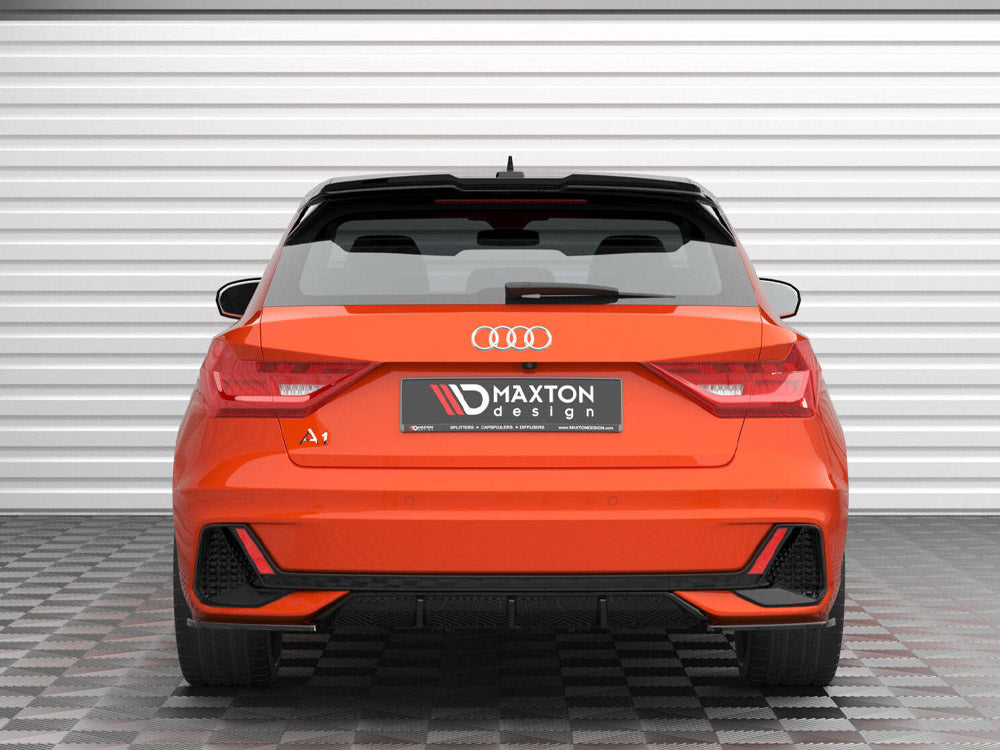 An orange Audi A1, parked on a checkered floor, faces a white garage door. The rear displays the logo and "Maxton Design" on the license plate area.