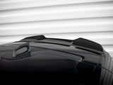 A black car roof features a shark fin antenna and two sleek air inlets. The background displays horizontal white ridges, resembling a garage door or wall paneling.
